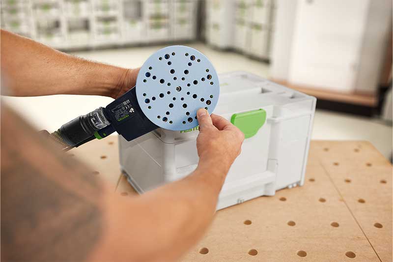 Ein Mann bring ein Granat Schleifmittel an dem Schleifteller an