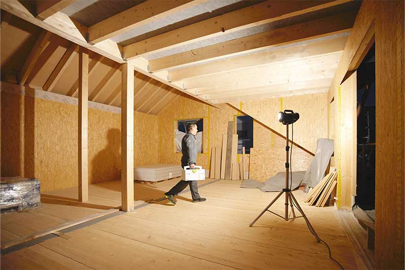 Ein Baustrahler leuchtet einen fensterlosen, dunklen Raum aus