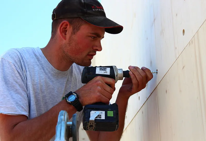 Ein Zimmermann verschraubt ein Wandelement mit dem Akku-Bohrschrauber DRC 18/4 von Festool.