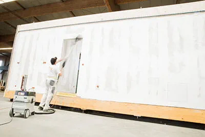 Die Wände der Fertighäuser werden mit dem Festool Langhalsschleifer bearbeitet.